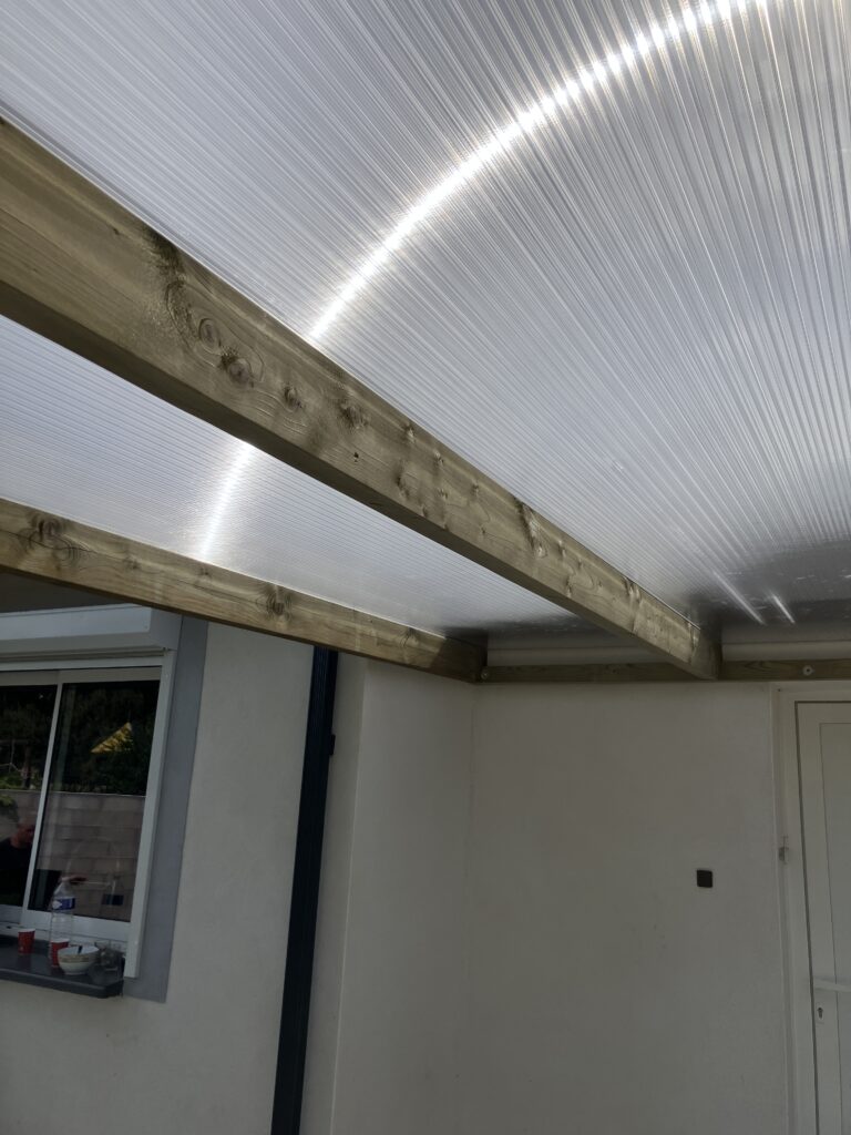 Toit en polycarbonate avec poutres apparentes en bois