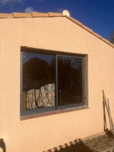 Fenêtre en verre sur mur extérieur beige.